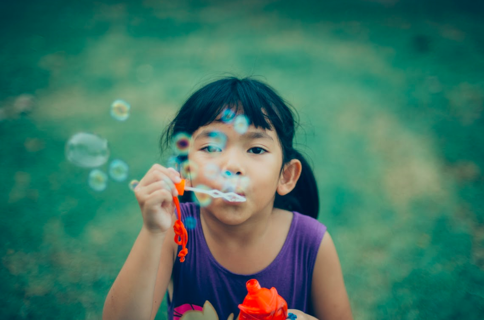 June Blog Post Image Young girl with bubbles at summer camp is happy she does not have lice because her parents followed summer lice prevention tips